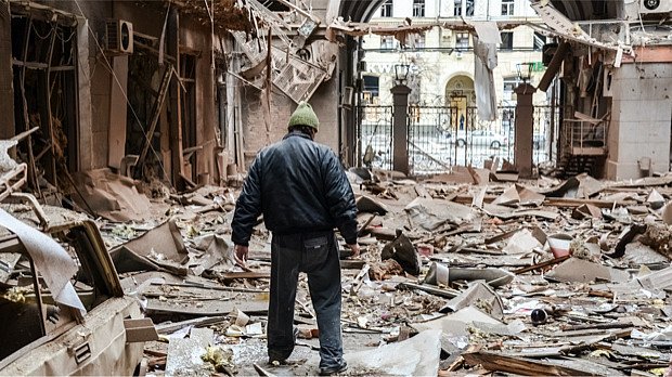 Ein Mann steht nach Kampfhandlungen in Trümmern.